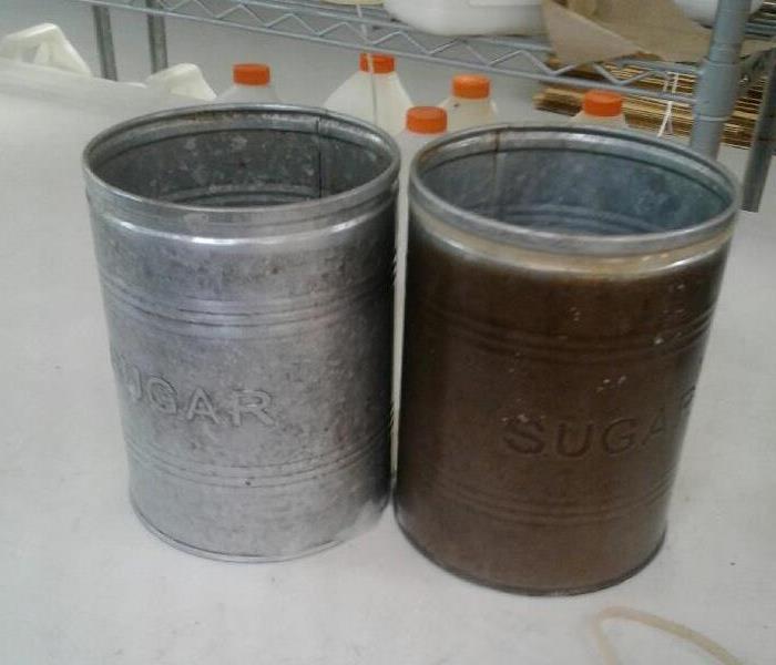 A pair of antique sugar cans next to each other where one has been cleaned and the other hasn't.